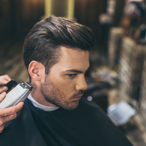 A man is getting his hair cut by a barber with a clipper.