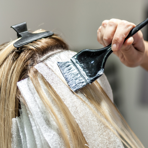 A woman is getting her hair dyed by a hairdresser.