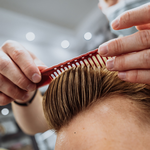 A man is getting his hair combed by a barber