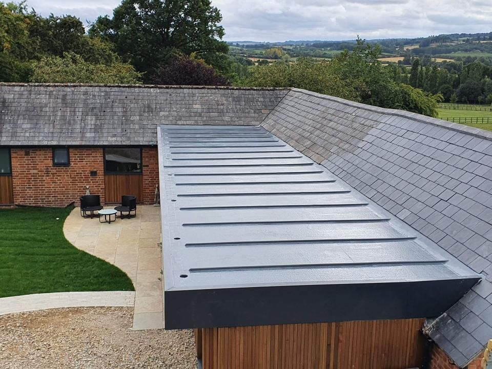 Modern building with grey flat roof and slate roof, exterior view of brick and wood siding.