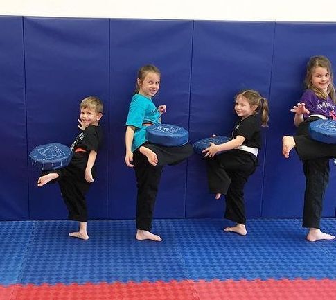 A group of young children are practicing martial arts on a mat.