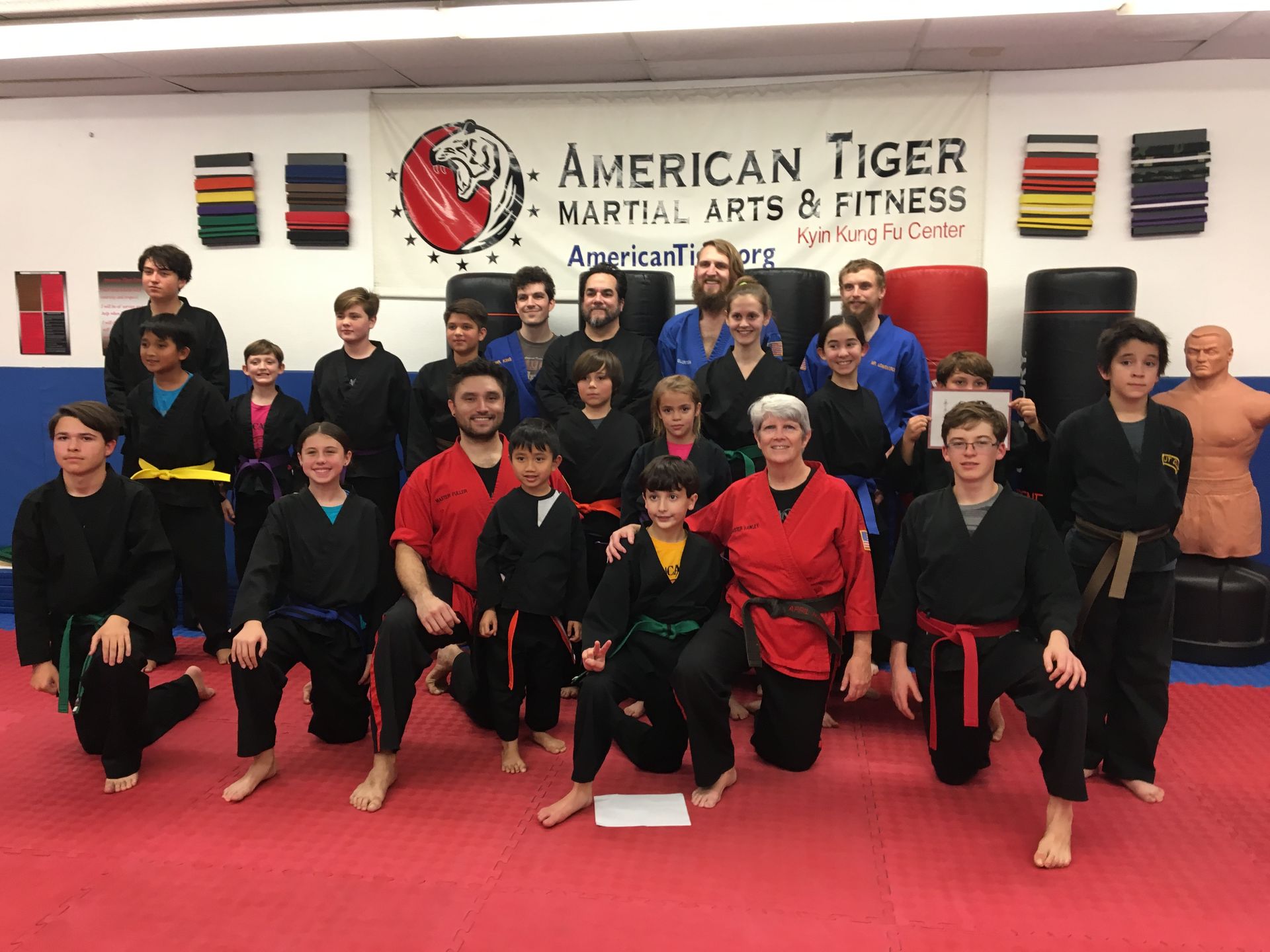A group of people are posing for a picture in front of a sign that says american tiger martial arts & fitness.
