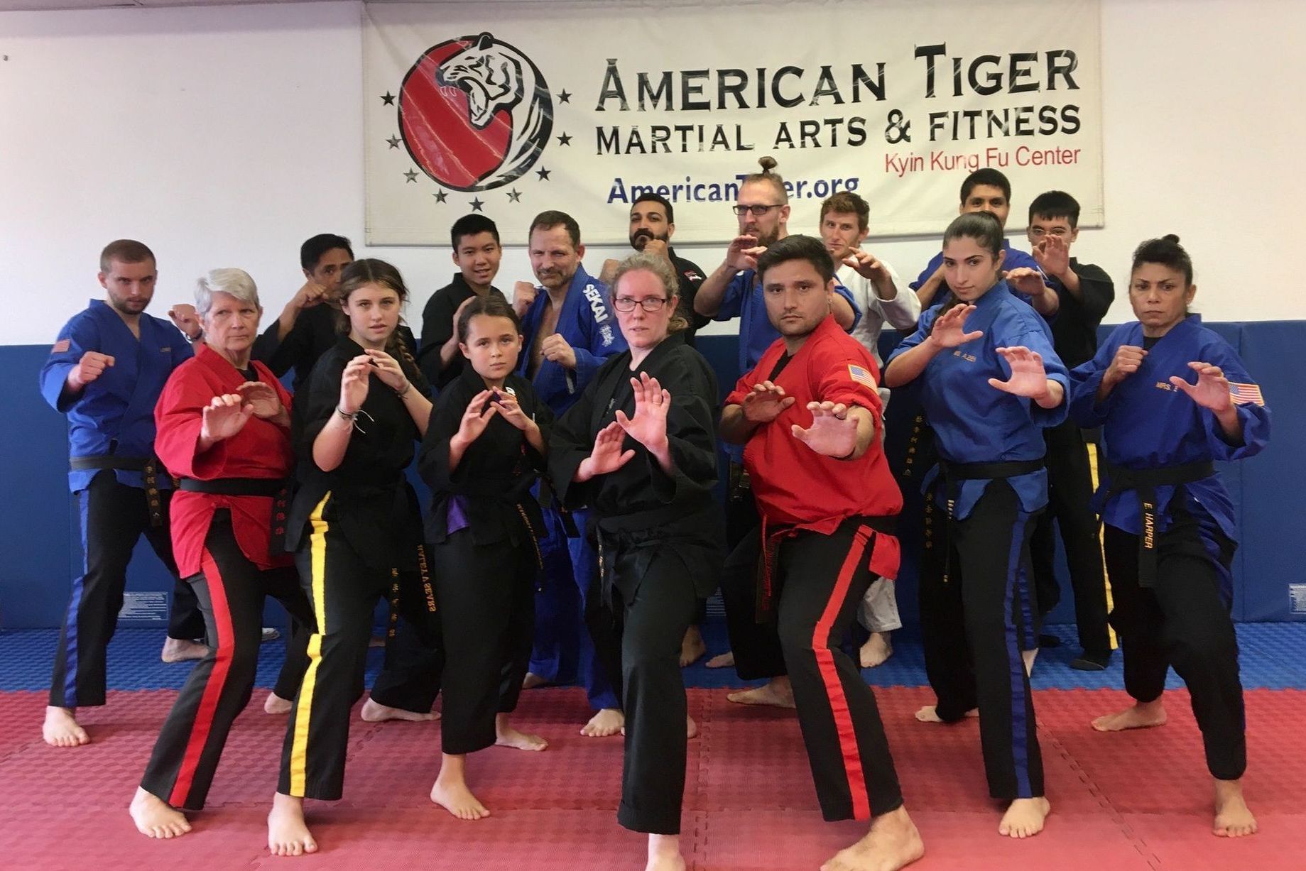 A group of people are standing in front of a sign that says american tiger martial arts & fitness