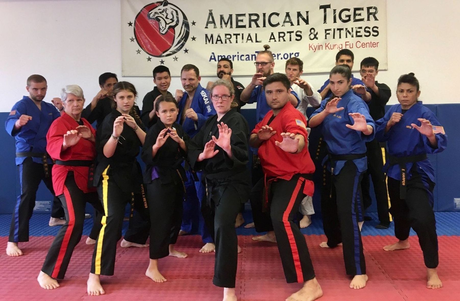 A group of people standing in front of a sign that says american tiger martial arts & fitness