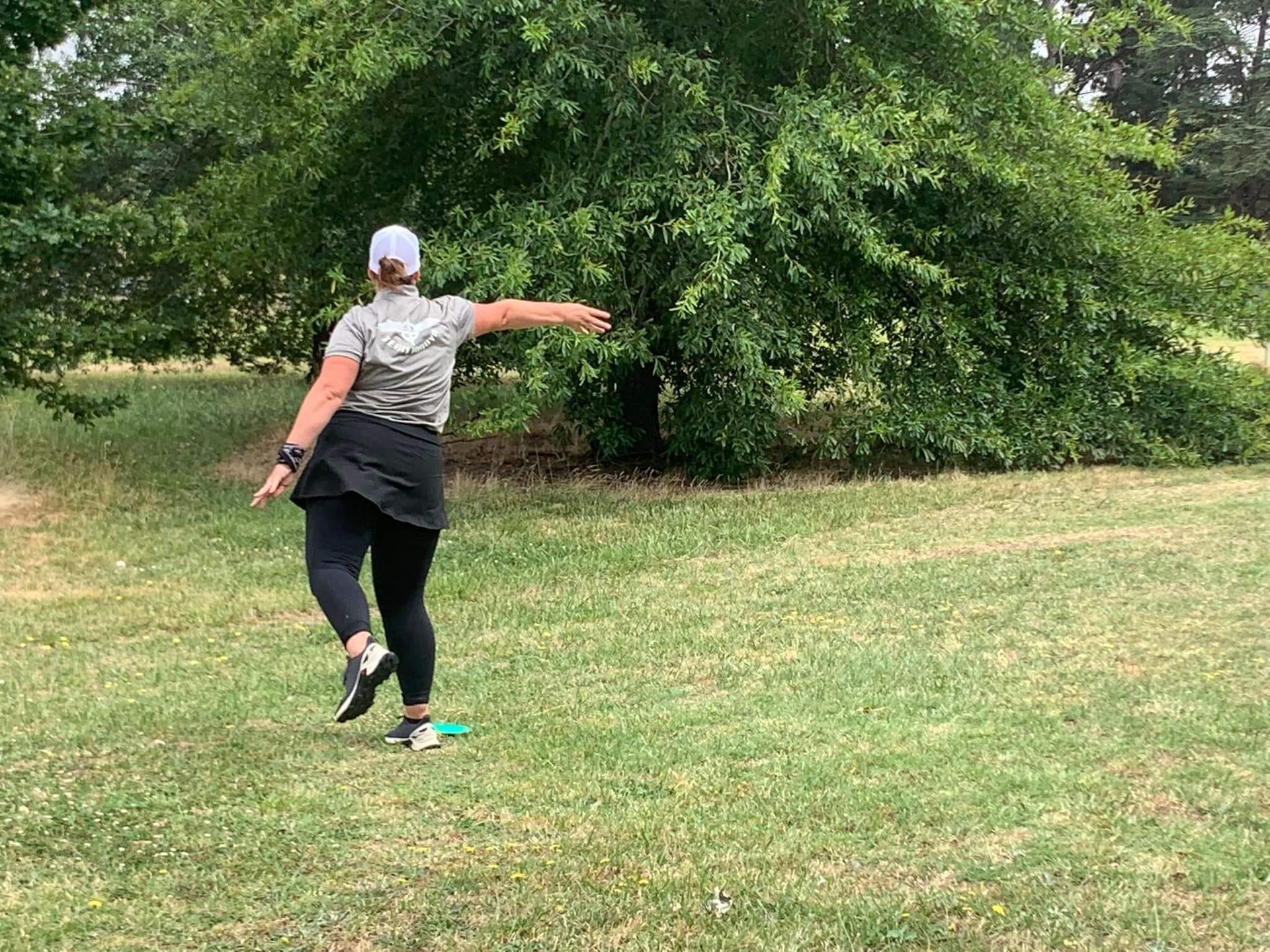 a woman is throwing a frisbee in a park .