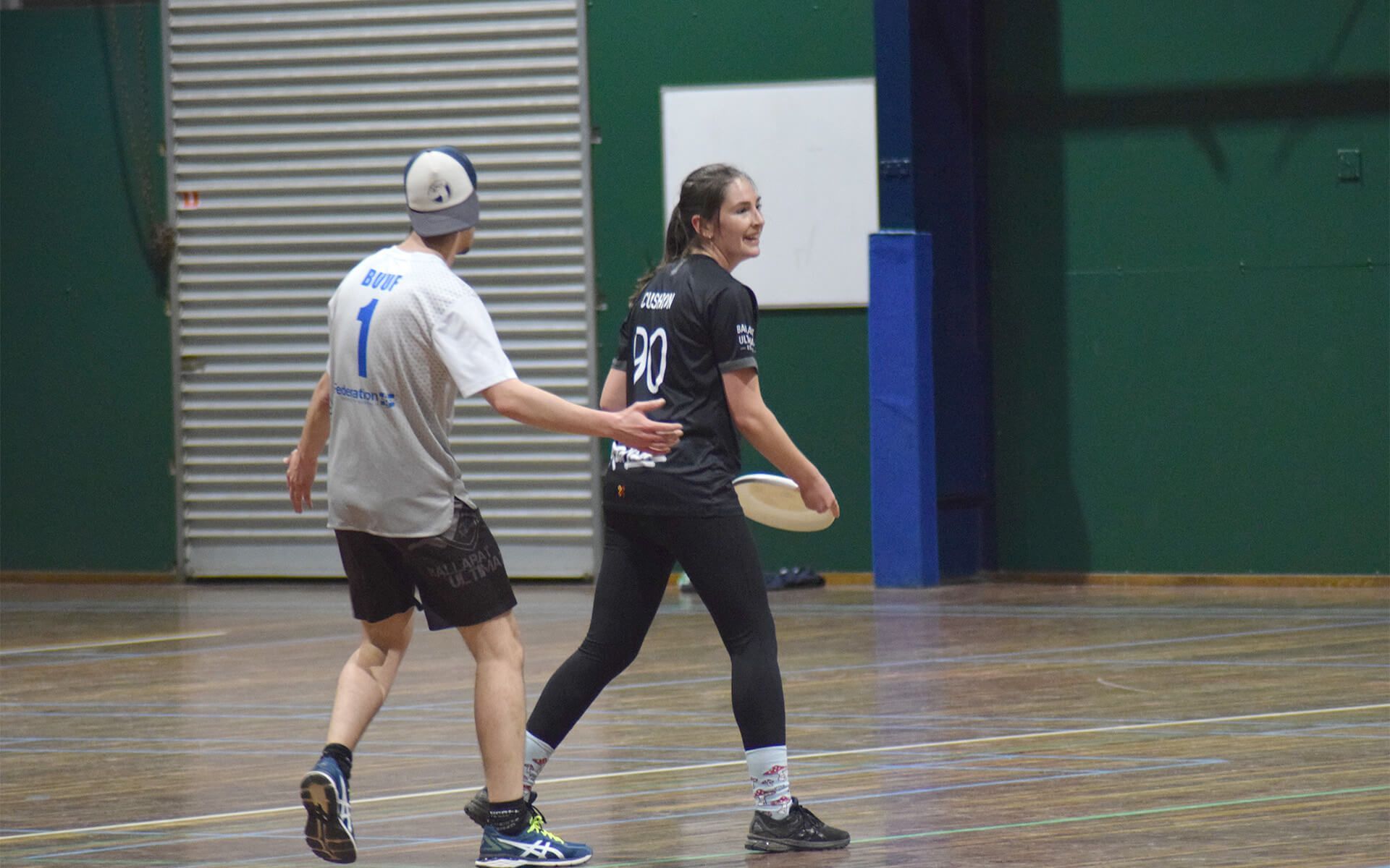 a man and a woman are playing frisbee on a court .