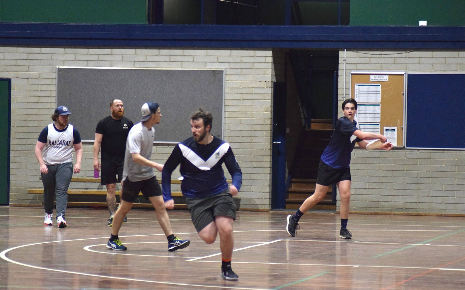 a group of men are playing basketball in a gym .