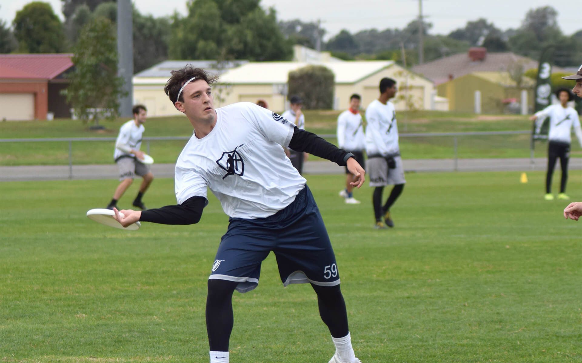 a man in a white shirt and blue shorts is throwing a frisbee on a field .