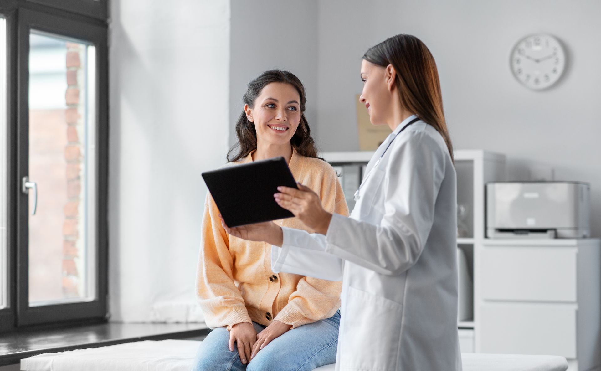 A doctor is talking to a patient while holding a tablet.