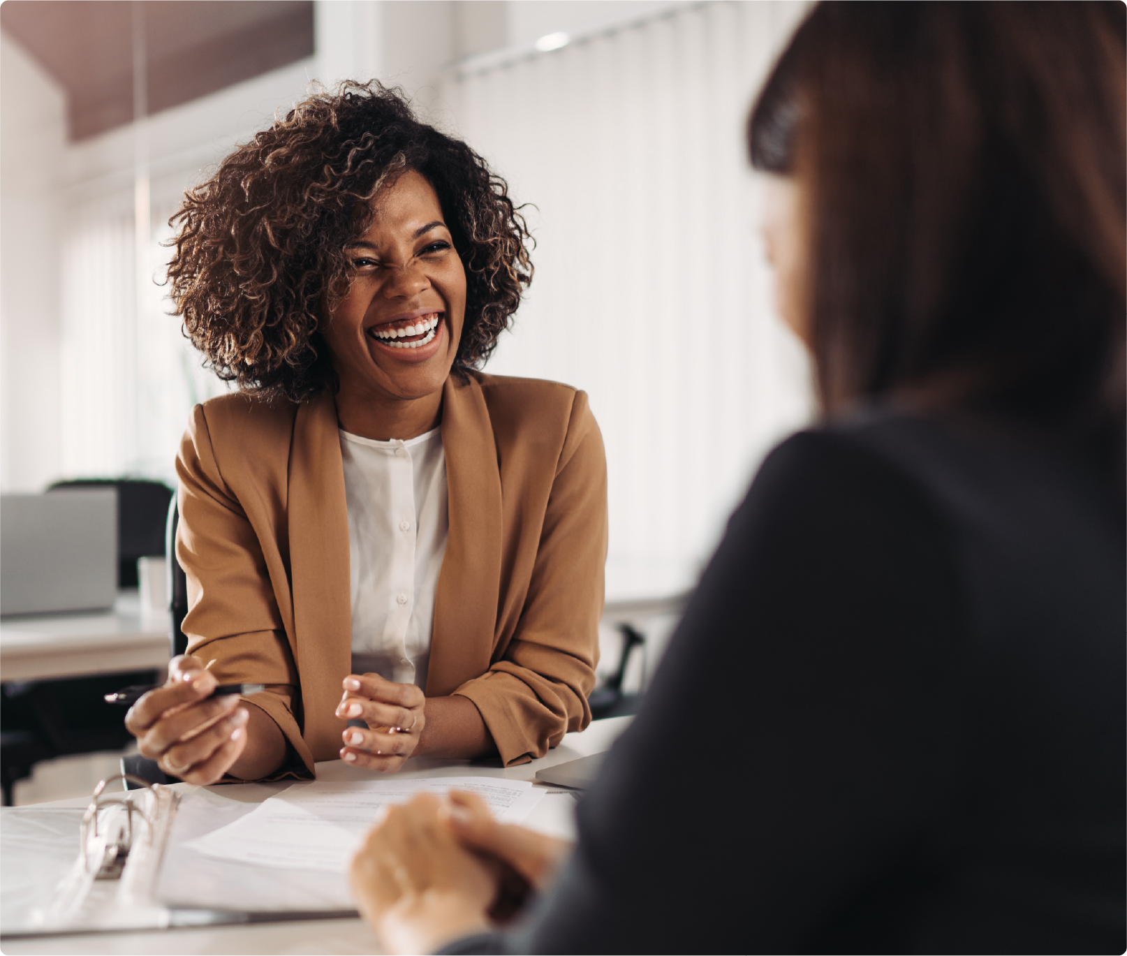 A woman is sitting at a table talking to another woman.