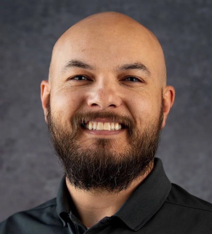 A bald man with a beard is smiling for the camera.