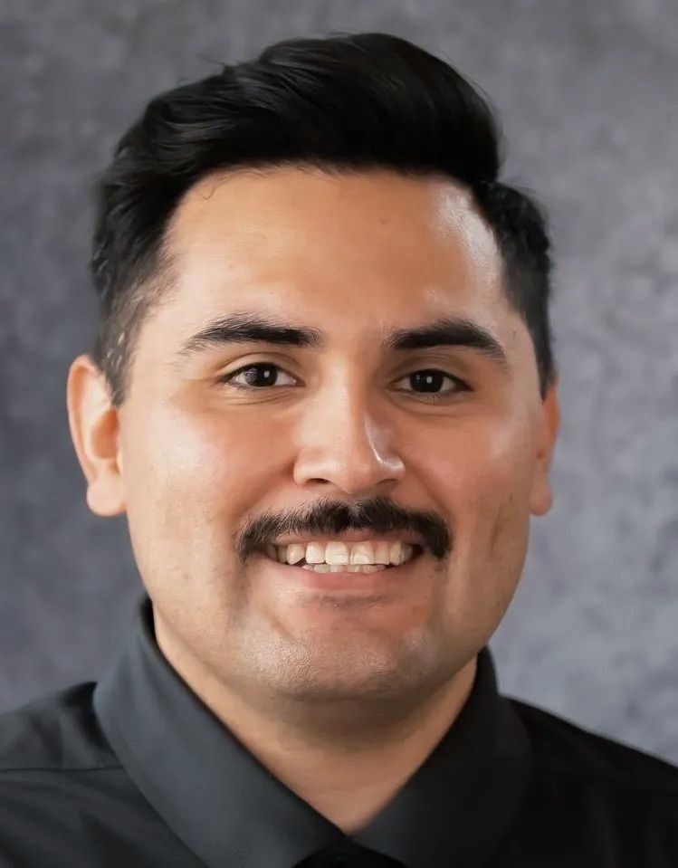 A man with a mustache and a black shirt is smiling for the camera.