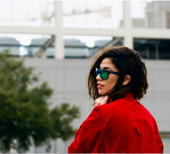 A woman wearing sunglasses and a red jacket looks over her shoulder