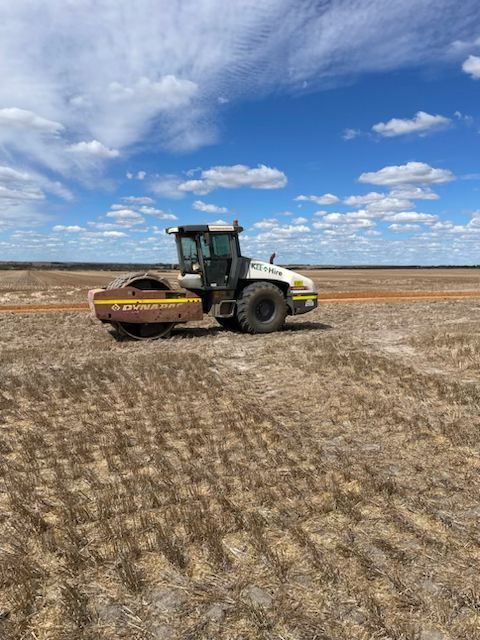 A tractor is driving through a dry field.