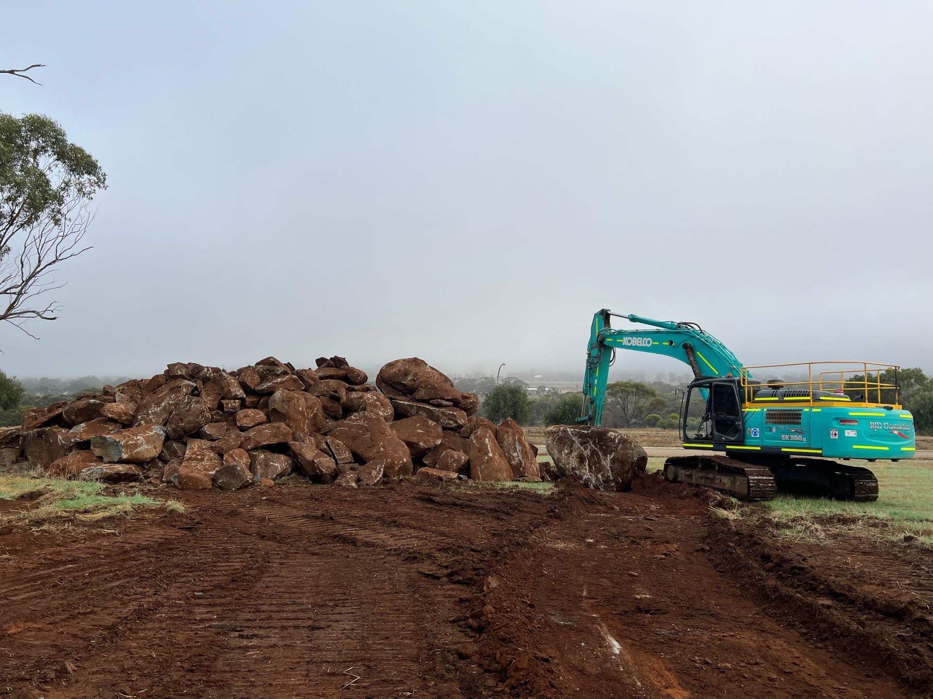 A large excavator is working on a pile of rocks.