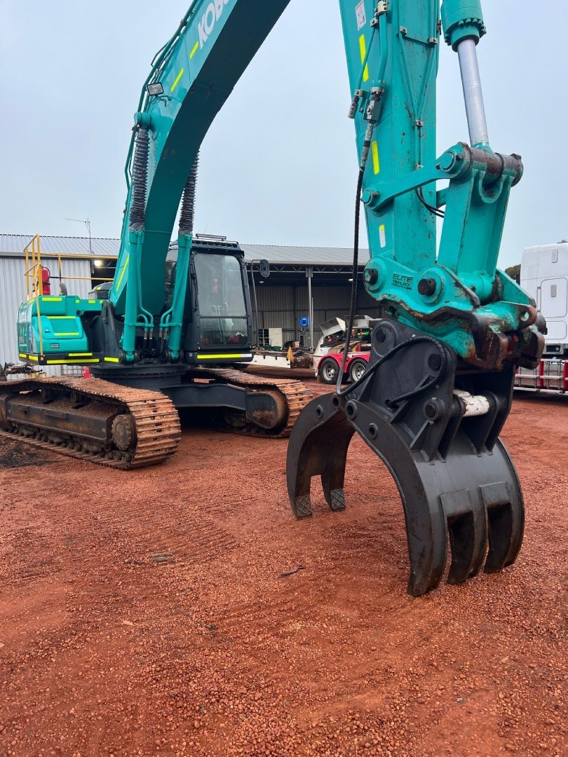 A large excavator is sitting on top of a dirt field.