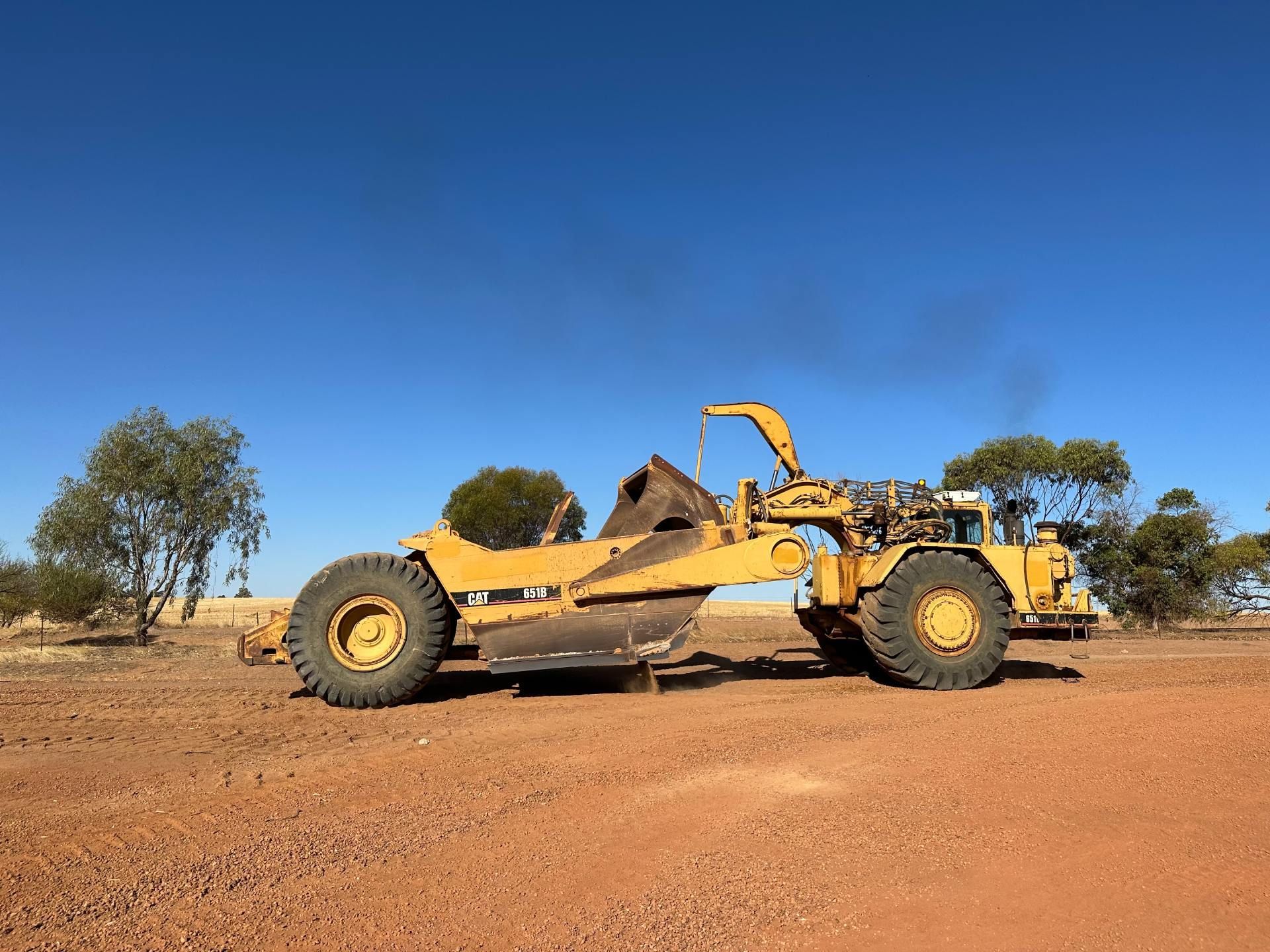 A yellow bulldozer is sitting in the middle of a dirt field.