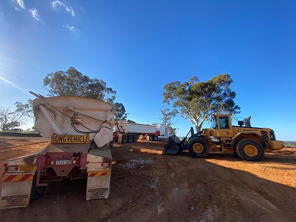 A truck and a bulldozer are parked next to each other on a dirt road.
