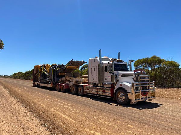 A large semi truck is driving down a dirt road.