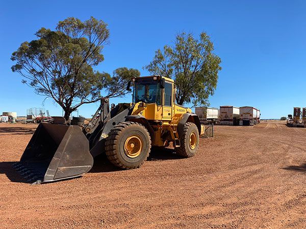 A yellow bulldozer is parked in a dirt field
