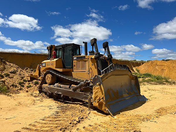 A bulldozer is sitting in the middle of a dirt field.
