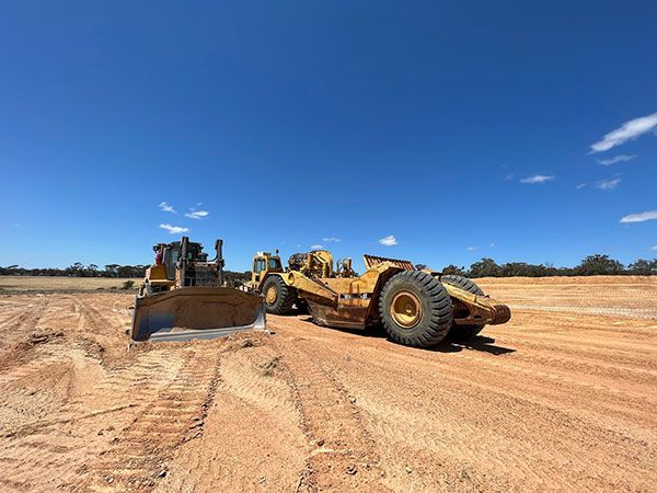 A bulldozer and a tractor are working on a dirt field.