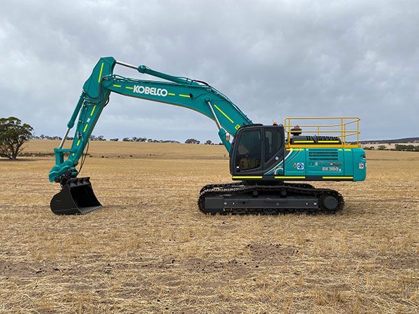 A blue and yellow excavator is parked in a field.