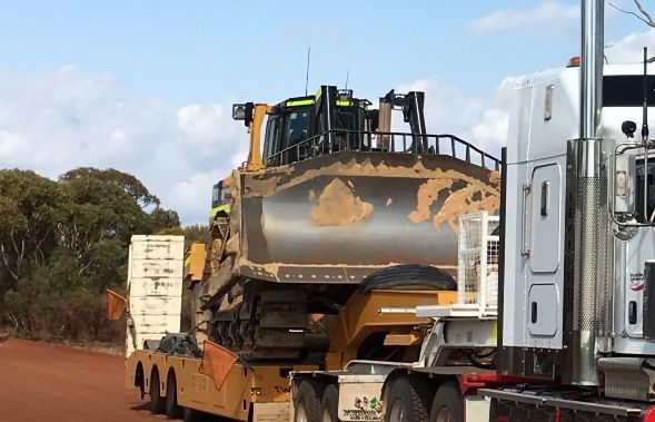 A bulldozer is being transported on the back of a semi truck.