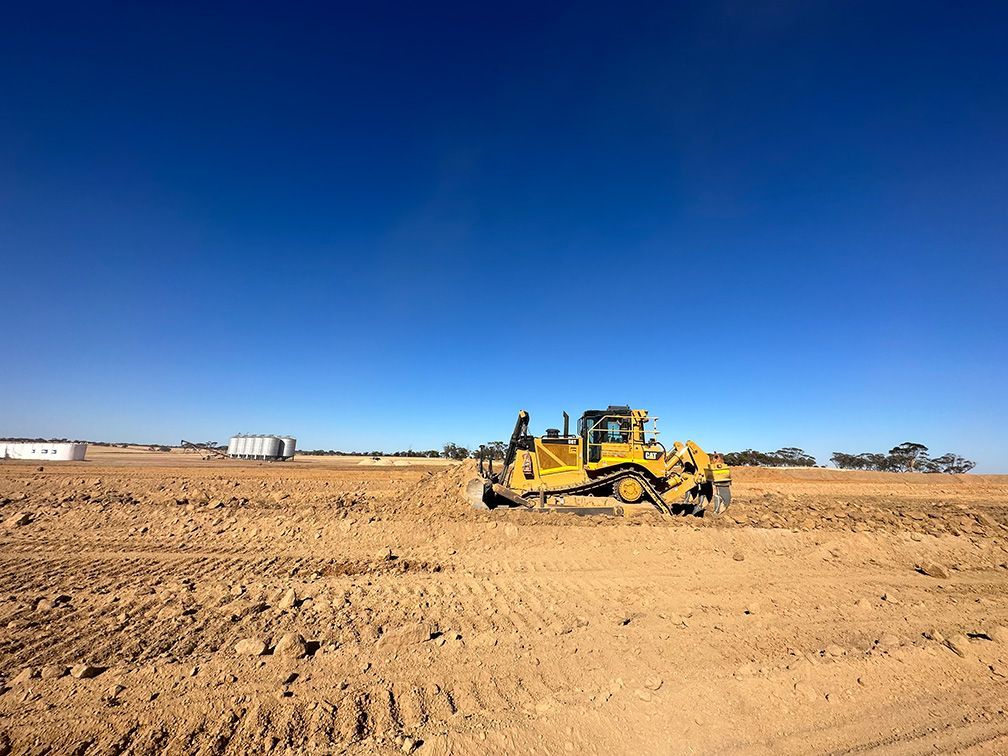 A bulldozer is sitting in the middle of a dirt field.