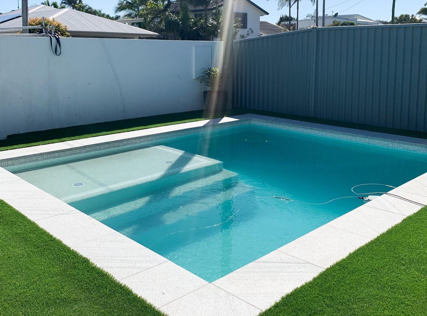 A Rectangular Swimming Pool Surrounded by Artificial Green Grass — Mad Pool Interiors and Renovations in Baringa, QLD