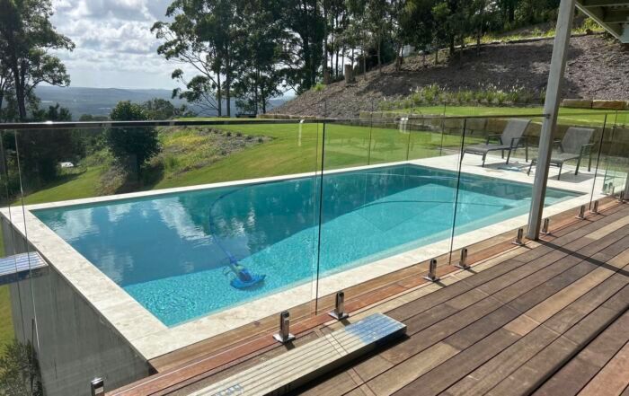 Outdoor Pool with Clear Blue Water and A Glass Fence — Mad Pool Interiors and Renovations in Baringa, QLD