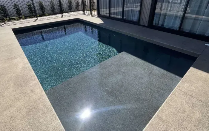 Modern Backyard Pool with Clear Blue Water, Tiled Deck, and Glass Fence — Mad Pool Interiors and Renovations in Baringa, QLD