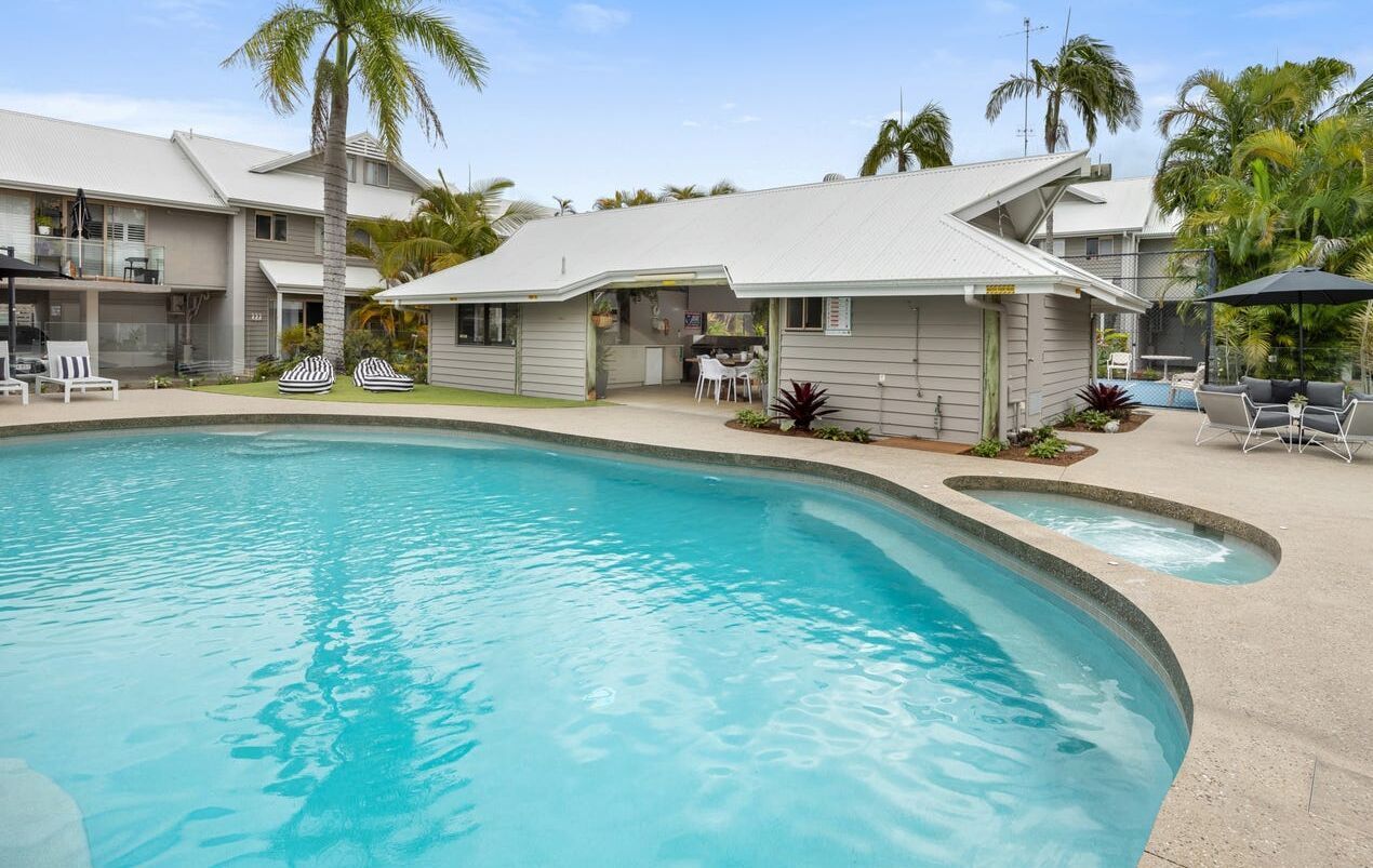 Swimming Pool and Spa With Poolside Buildings and Palm Trees — Mad Pool Interiors and Renovations in Baringa, QLD