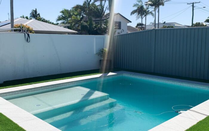 Backyard Swimming Pool with Turquoise Water Beside a White Fence — Mad Pool Interiors and Renovations in Baringa, QLD