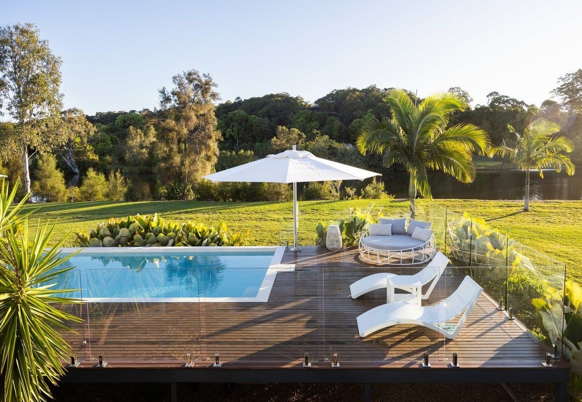 Poolside Scene With Pool, Loungers, Umbrella, and Lush Greenery — Mad Pool Interiors and Renovations in Baringa, QLD