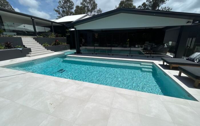 Modern House with A Turquoise Swimming Pool and Wide Stone Patio — Mad Pool Interiors and Renovations in Baringa, QLD