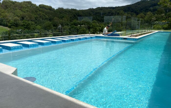 Outdoor Infinity Pool with Bright Blue Water — Mad Pool Interiors and Renovations in Baringa, QLD