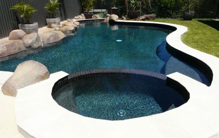 Curved Backyard Swimming Pool with Attached Spa — Mad Pool Interiors and Renovations in Baringa, QLD