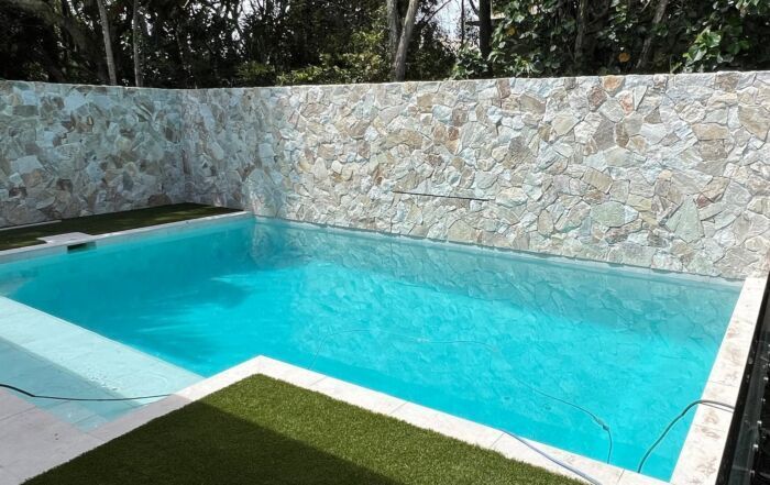 Turquoise Swimming Pool with Stone Walls — Mad Pool Interiors and Renovations in Baringa, QLD