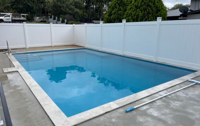 Backyard Swimming Pool with Blue Water, White Privacy Fence, and Concrete Deck — Mad Pool Interiors and Renovations in Baringa, QLD