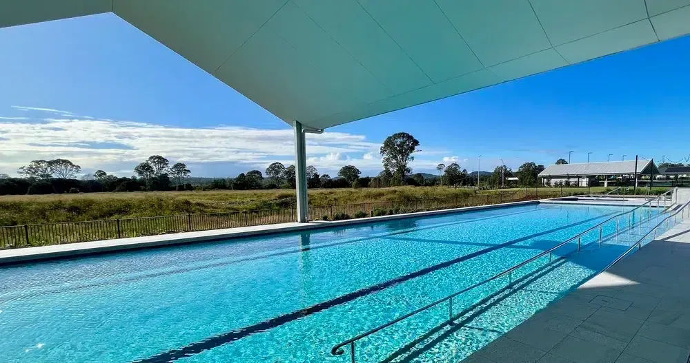 Long, Turquoise Outdoor Pool Under a White Awning, Blue Sky Background — Mad Pool Interiors and Renovations in Baringa, QLD