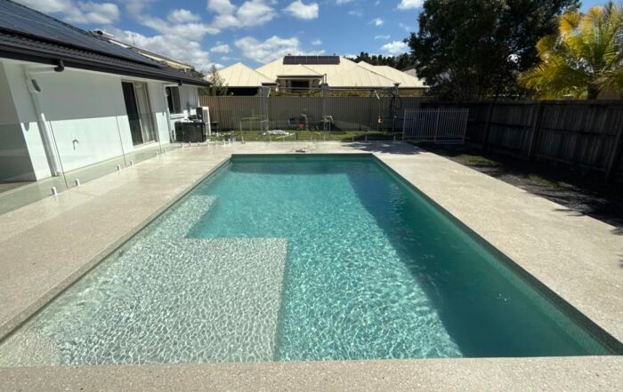 Backyard Swimming Pool with Turquoise Water Beside a House and Fenced Yard — Mad Pool Interiors and Renovations in Baringa, QLD