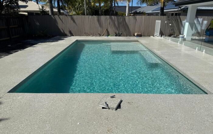 Modern Backyard Pool with Turquoise Water and Light Stone Decking — Mad Pool Interiors and Renovations in Baringa, QLD