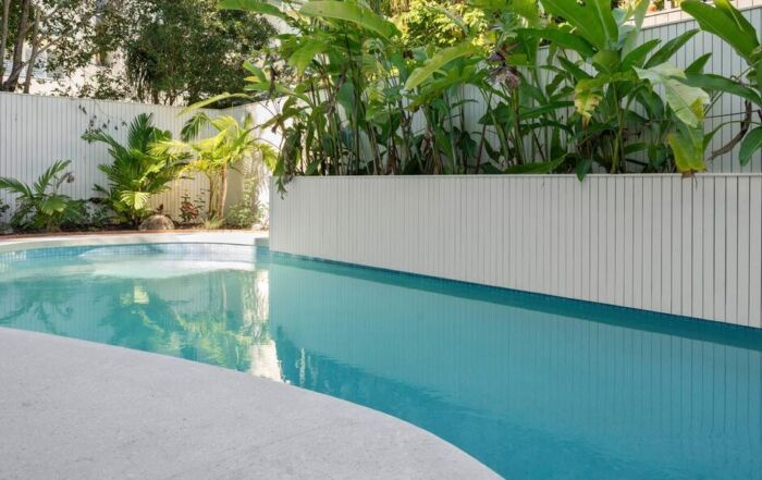 Modern Backyard Pool with Turquoise Water, White Deck, and Lush Tropical Plants — Mad Pool Interiors and Renovations in Baringa, QLD