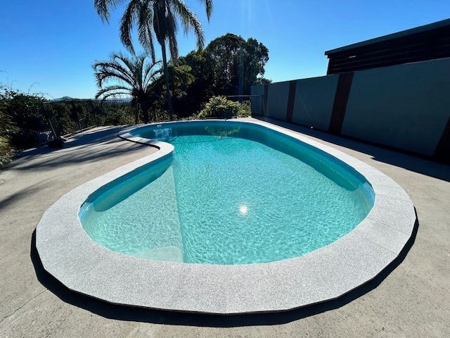 Swimming Pool With Light Blue Water and a Speckled Concrete Border — Mad Pool Interiors and Renovations in Baringa, QLD