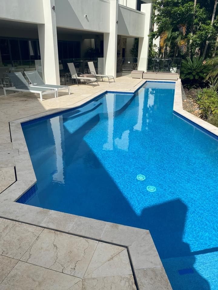 Modern Outdoor Swimming Pool With Blue Water Beside a Patio — Mad Pool Interiors and Renovations in Baringa, QLD