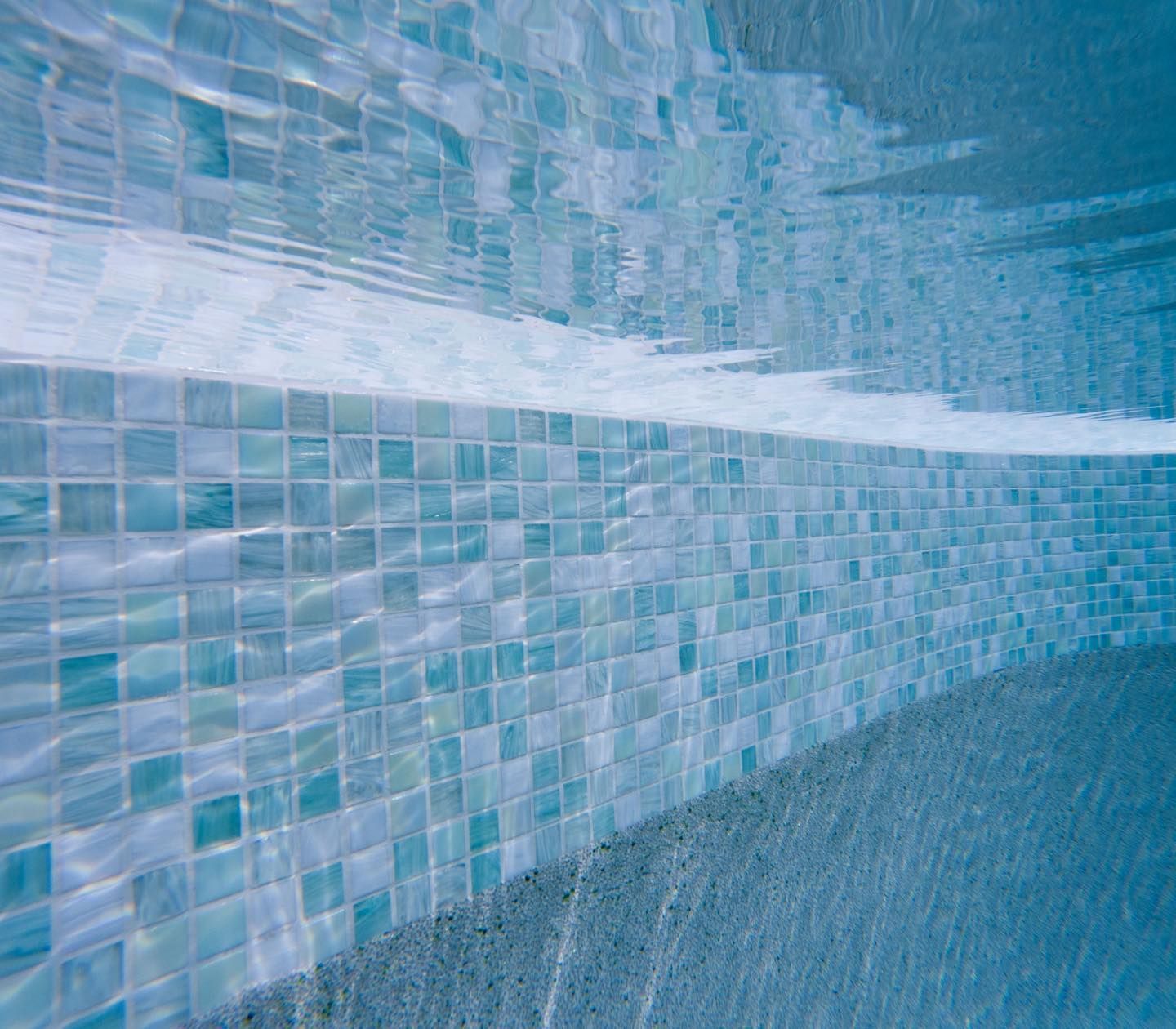 Blue Tiled Swimming Pool Wall With Rippling Water — Mad Pool Interiors and Renovations in Baringa, QLD