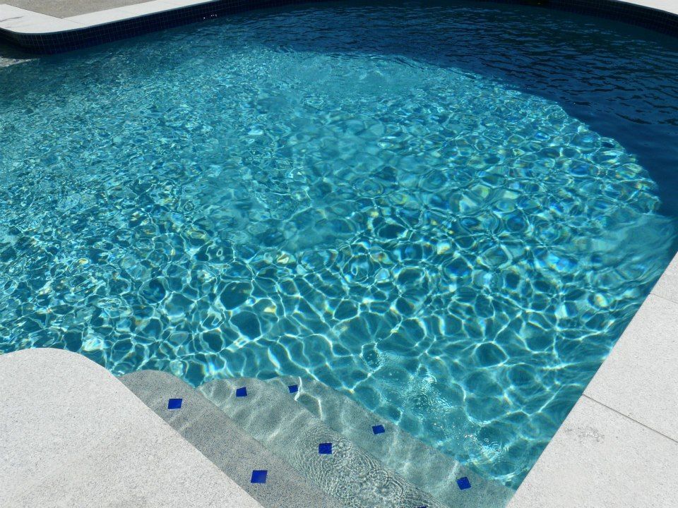 Blue Swimming Pool With Clear Rippling Water — Mad Pool Interiors and Renovations in Baringa, QLD