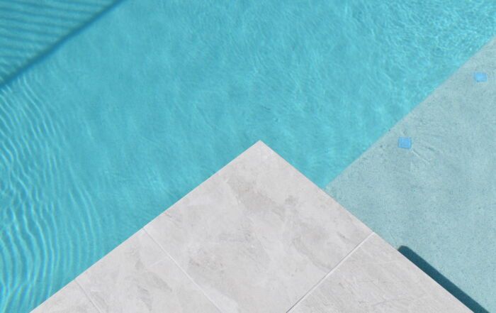 Turquoise Swimming Pool Water Beside a Light Stone Pool Edge — Mad Pool Interiors and Renovations in Baringa, QLD