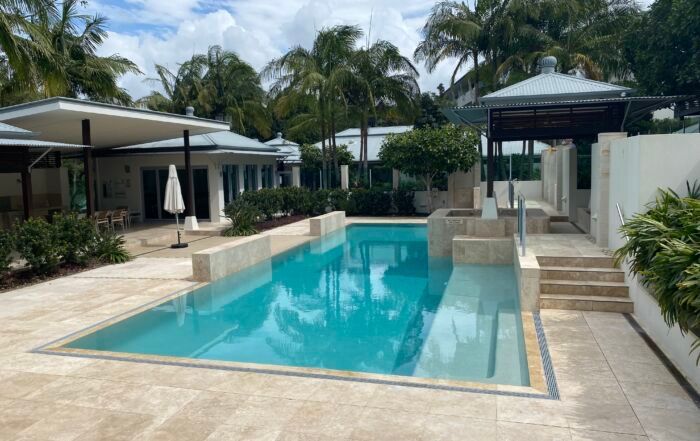 Outdoor Swimming Pool with Turquoise Water, Palm Trees, and A Modern Patio — Mad Pool Interiors and Renovations in Baringa, QLD
